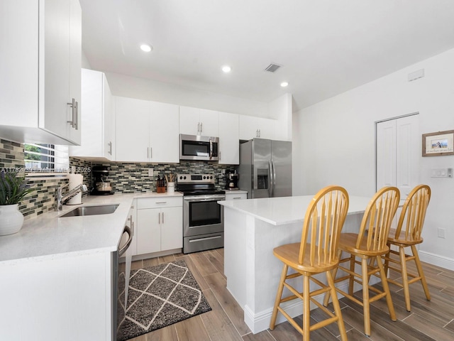 kitchen with visible vents, a breakfast bar, a sink, stainless steel appliances, and light wood-style floors