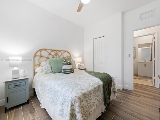 bedroom featuring wood finished floors, visible vents, baseboards, ceiling fan, and a closet