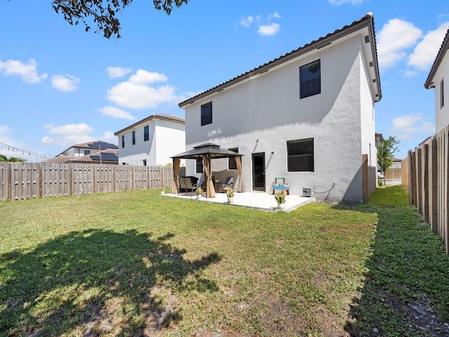 rear view of property featuring a gazebo, stucco siding, a patio, and a lawn