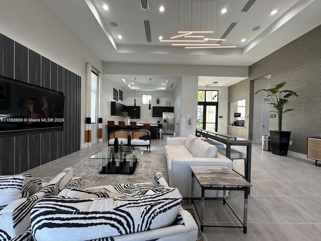 living area featuring visible vents, wallpapered walls, a tray ceiling, recessed lighting, and an accent wall