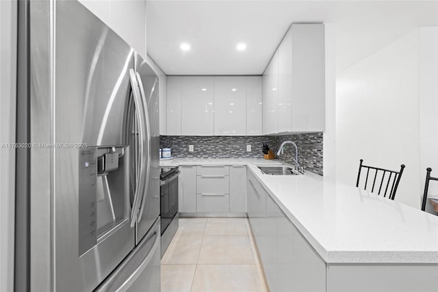 kitchen with modern cabinets, a sink, appliances with stainless steel finishes, a peninsula, and white cabinets