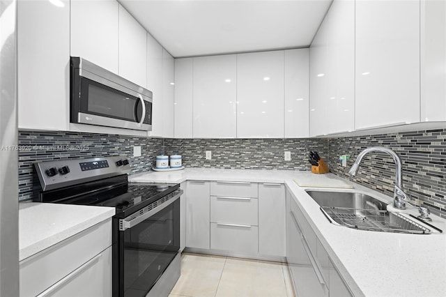 kitchen featuring a sink, decorative backsplash, appliances with stainless steel finishes, white cabinetry, and modern cabinets