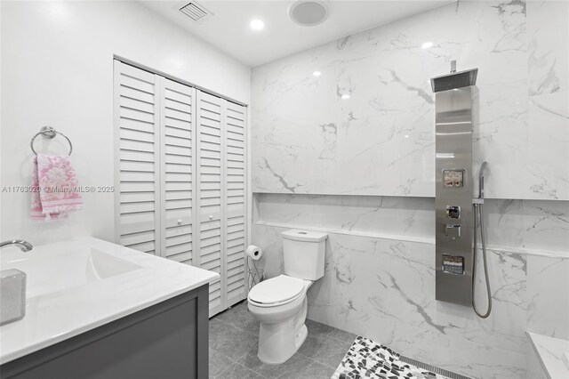 bathroom with vanity, visible vents, a marble finish shower, tile walls, and toilet