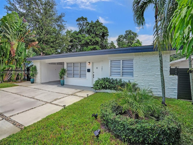 view of front facade with a carport, concrete driveway, fence, and a front yard