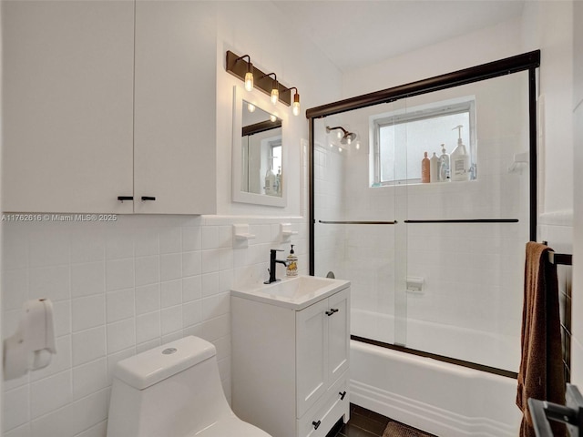 bathroom featuring a wainscoted wall, toilet, tile walls, bath / shower combo with glass door, and vanity