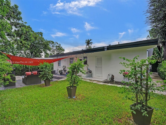 back of property featuring outdoor lounge area, a yard, and stucco siding