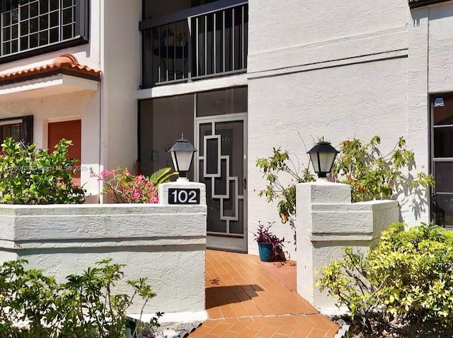 view of exterior entry with stucco siding and a tiled roof