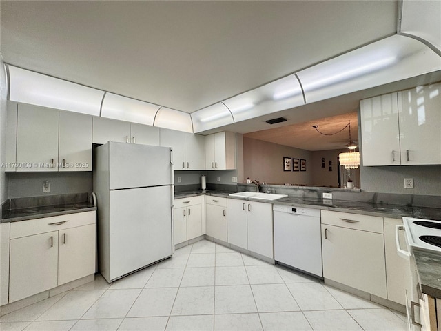 kitchen with visible vents, a sink, dark countertops, white appliances, and light tile patterned floors