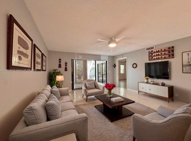 living room featuring tile patterned floors, a ceiling fan, visible vents, and a textured ceiling