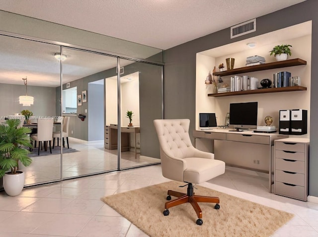 office space with light tile patterned floors, visible vents, a textured ceiling, and baseboards