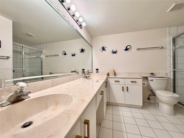 bathroom featuring tile patterned flooring, toilet, a stall shower, and a sink