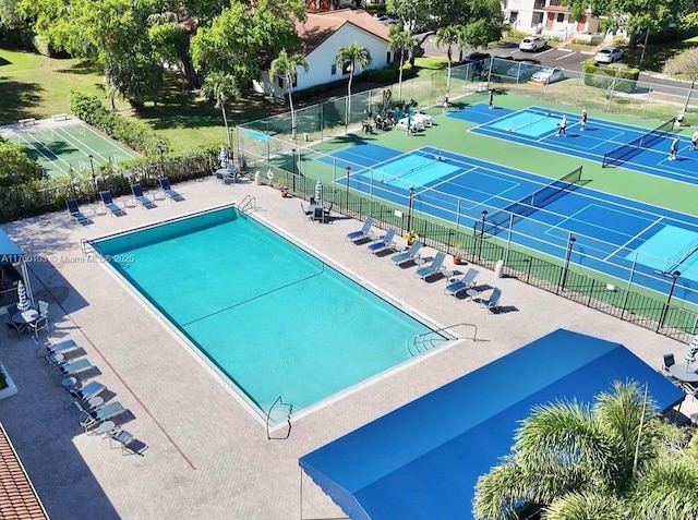 pool featuring a patio area, a tennis court, and fence