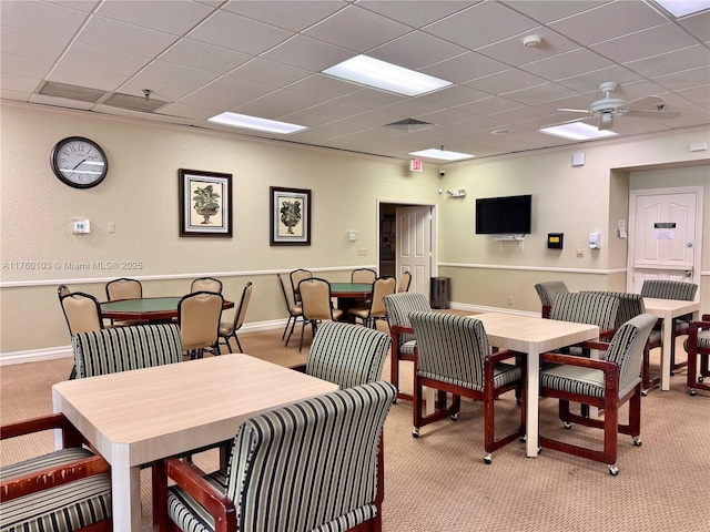 dining room with a drop ceiling, light colored carpet, baseboards, and ceiling fan