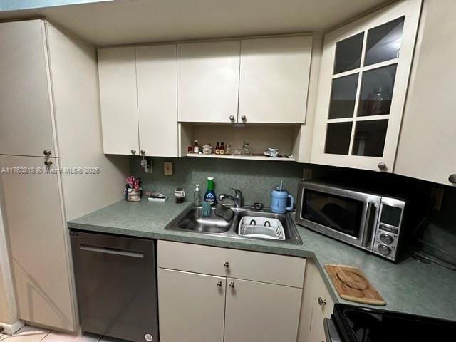 kitchen with a sink, stainless steel microwave, dishwasher, and white cabinets