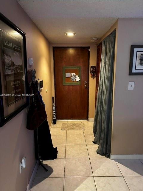 corridor with light tile patterned flooring and baseboards