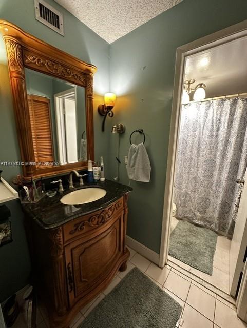 full bath with visible vents, toilet, vanity, tile patterned floors, and a textured ceiling