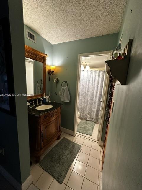 bathroom with vanity, tile patterned floors, visible vents, and a textured ceiling