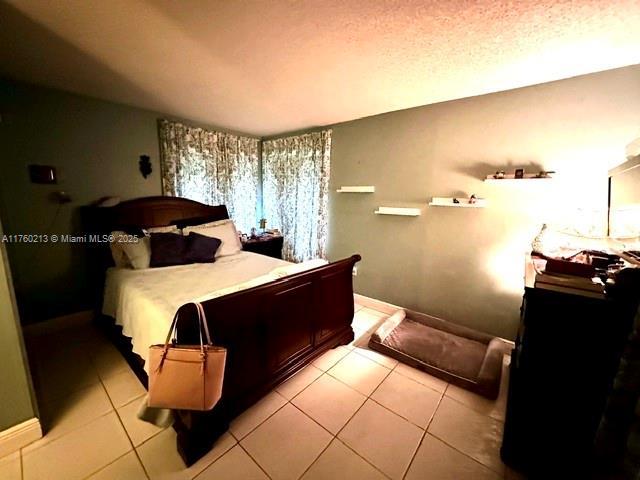 bedroom with light tile patterned flooring, baseboards, and a textured ceiling