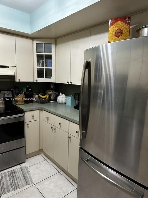 kitchen featuring under cabinet range hood, glass insert cabinets, appliances with stainless steel finishes, and white cabinets