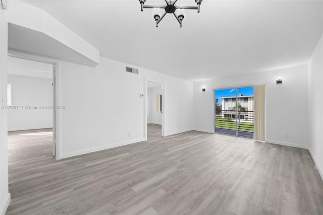 empty room featuring baseboards, visible vents, and light wood finished floors