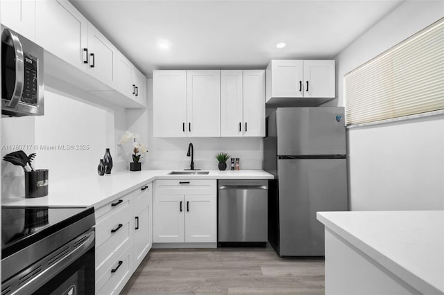 kitchen featuring light countertops, white cabinets, appliances with stainless steel finishes, and a sink