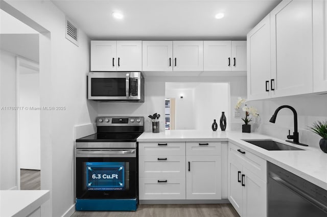 kitchen with visible vents, a sink, light countertops, white cabinets, and appliances with stainless steel finishes