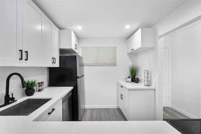 kitchen with a sink, wood finished floors, recessed lighting, appliances with stainless steel finishes, and white cabinets