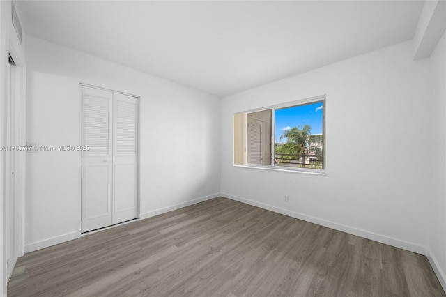 unfurnished bedroom with a closet, baseboards, and wood finished floors