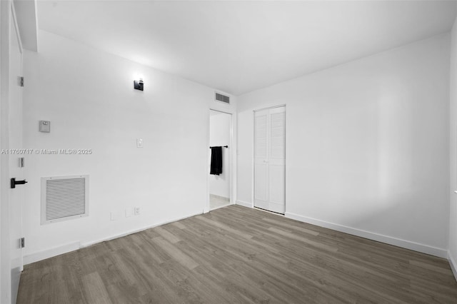 empty room with visible vents, baseboards, and wood finished floors