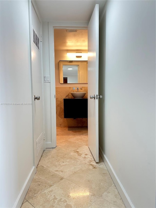 hallway featuring visible vents, baseboards, and a sink