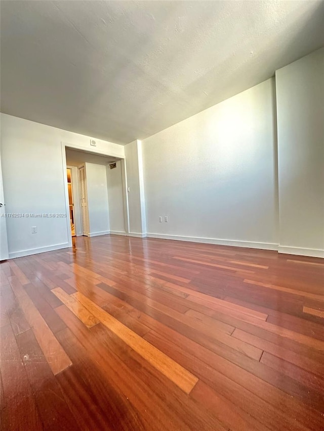 spare room featuring hardwood / wood-style floors, baseboards, and a textured ceiling