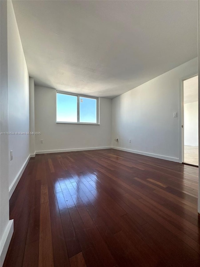 unfurnished room with baseboards and hardwood / wood-style floors