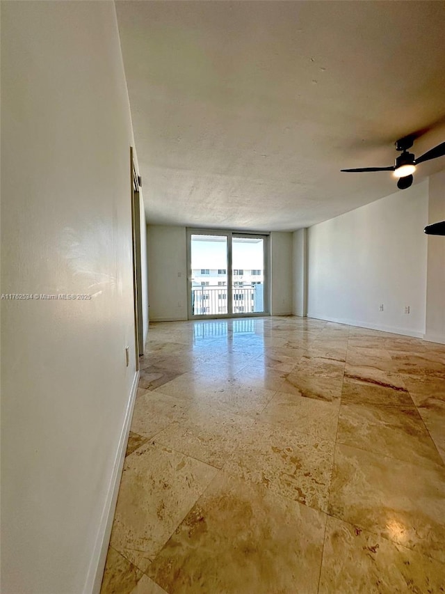 empty room featuring a ceiling fan and baseboards