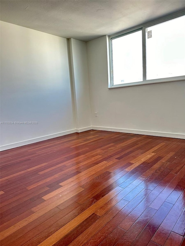 unfurnished room with dark wood finished floors and baseboards