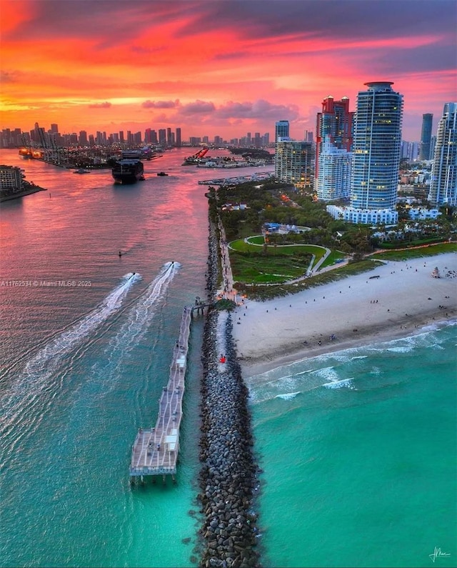 aerial view at dusk featuring a city view, a beach view, and a water view