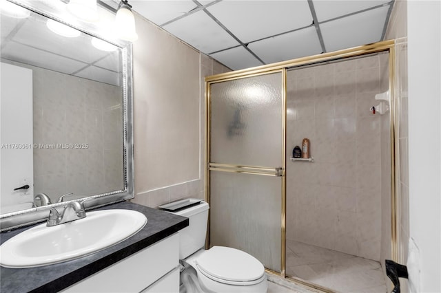 full bathroom with a drop ceiling, a shower stall, toilet, and vanity