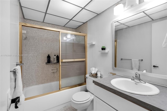 full bath with vanity, toilet, a paneled ceiling, and combined bath / shower with glass door