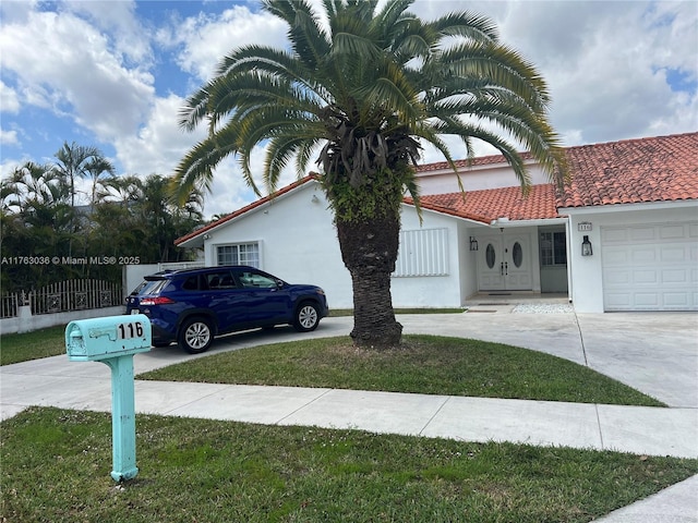 view of front of property featuring stucco siding, a garage, driveway, and a tiled roof