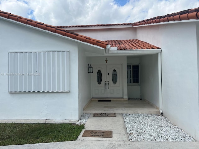 view of exterior entry featuring a tiled roof and stucco siding