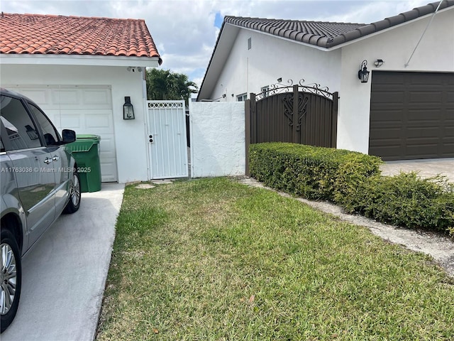 view of property exterior featuring a gate, a yard, an attached garage, stucco siding, and a tile roof