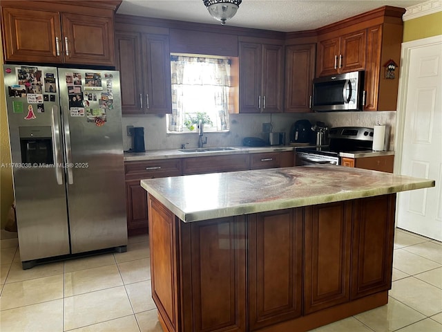 kitchen with a sink, appliances with stainless steel finishes, light tile patterned floors, and light countertops