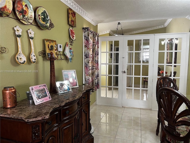 entryway with a textured ceiling, french doors, crown molding, light tile patterned floors, and lofted ceiling