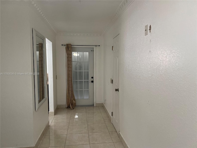 corridor with light tile patterned floors, baseboards, and ornamental molding