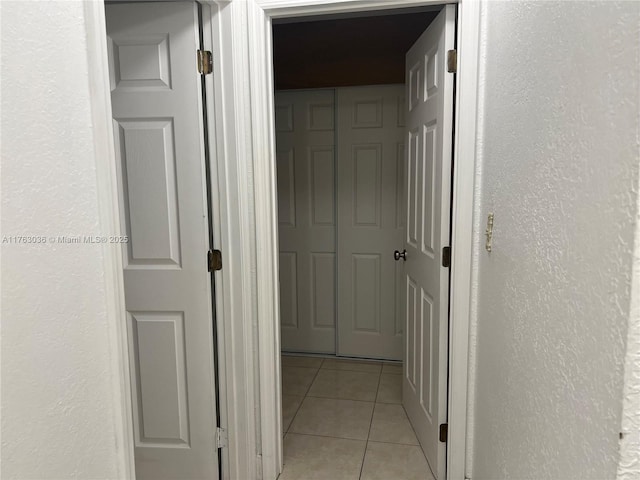 hallway featuring light tile patterned flooring and a textured wall