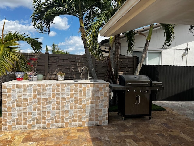 view of patio with grilling area, fence, and a sink