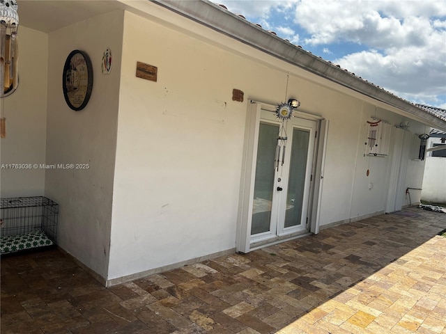 doorway to property with a patio, french doors, and stucco siding