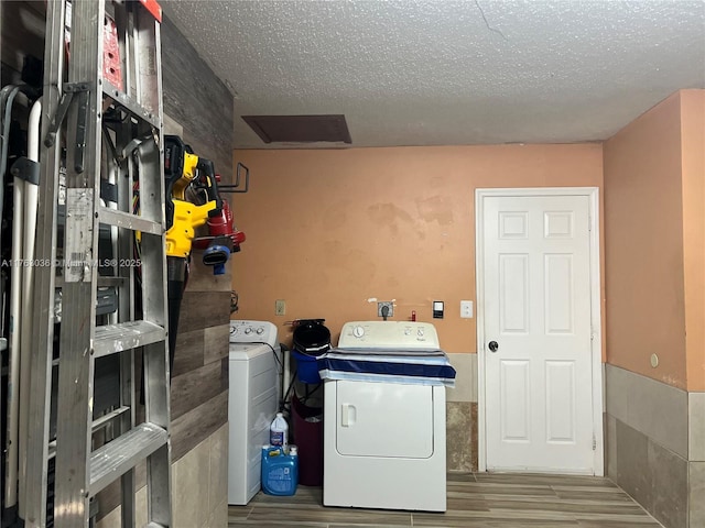 laundry room with washer and clothes dryer, laundry area, a textured ceiling, and wood finished floors