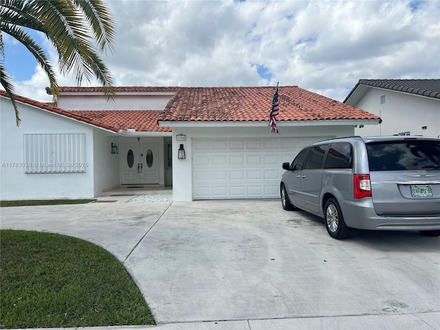 mediterranean / spanish-style home with a tiled roof, a garage, driveway, and stucco siding