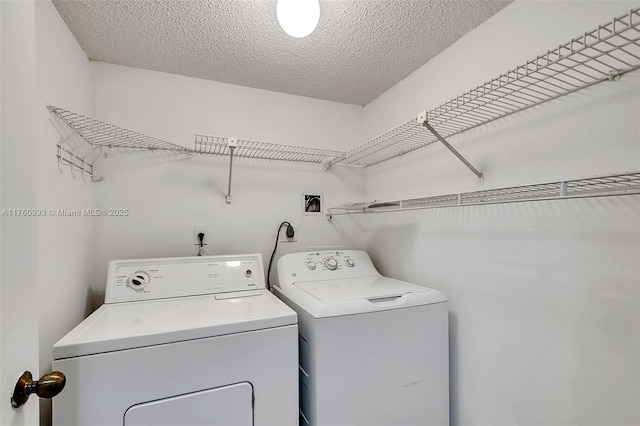 washroom featuring laundry area, washer and dryer, and a textured ceiling