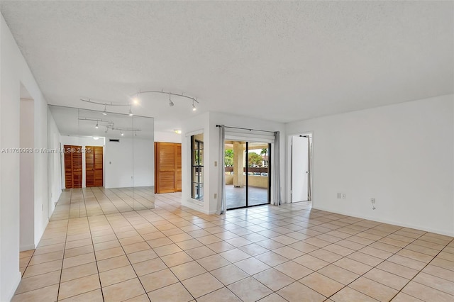 spare room featuring light tile patterned floors, track lighting, and a textured ceiling
